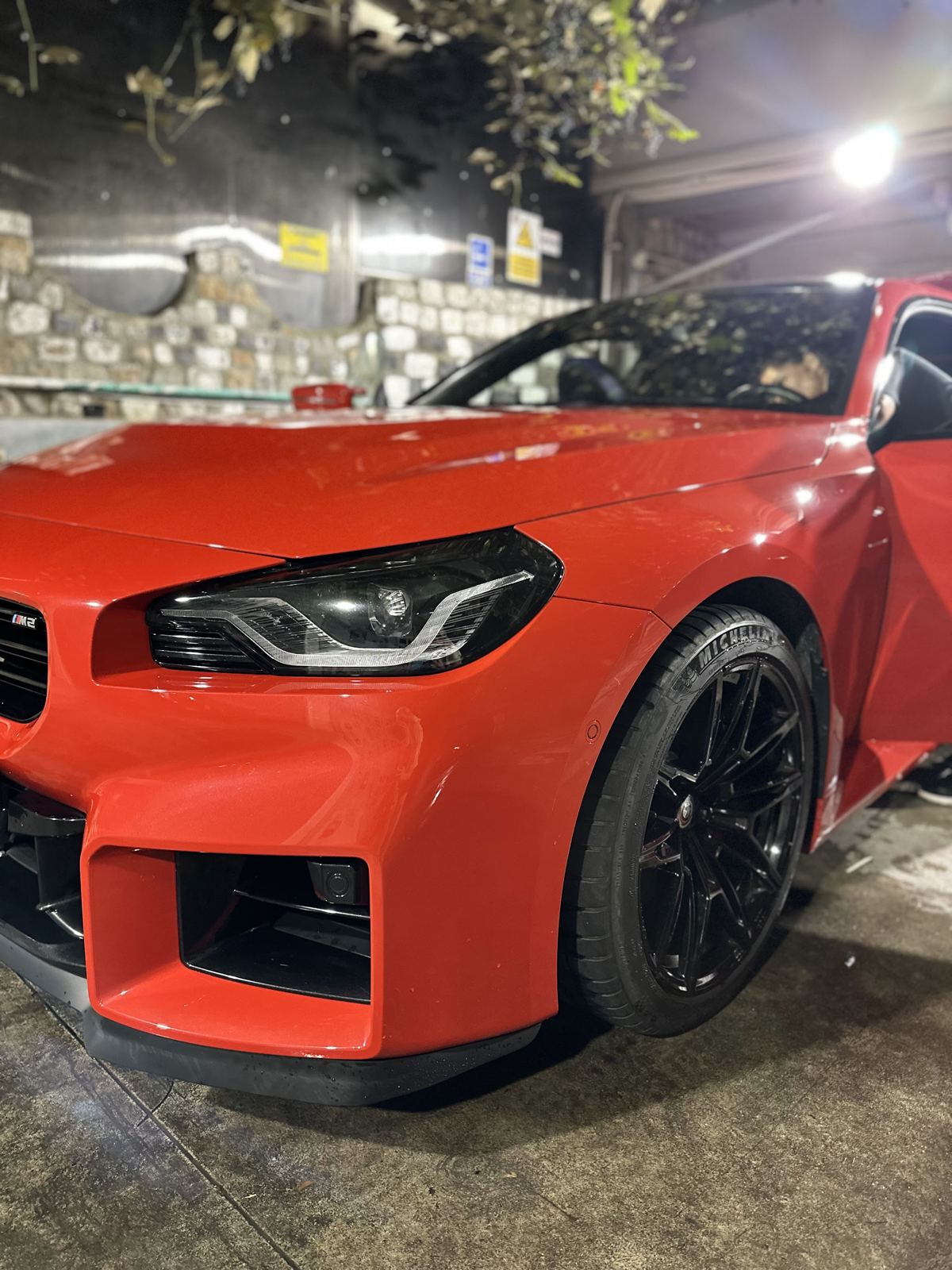 BMW M2 roșu, proaspăt spălat, seara